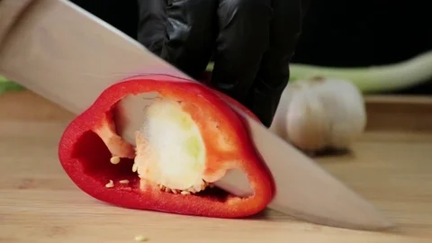 A cook cuts a red pepper with a sharp knife on a cutting board Stock Footage 127196876