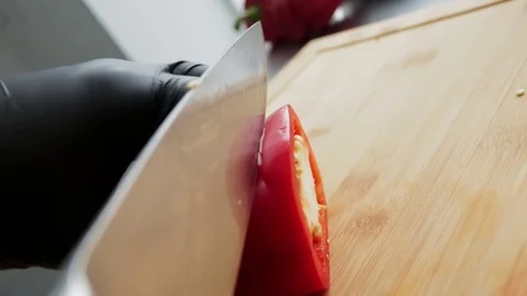 A cook cuts a red pepper with a sharp knife on a cutting board Stock Footage 127204406