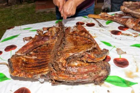 The cook cuts a roasted lamb. Stock Photos