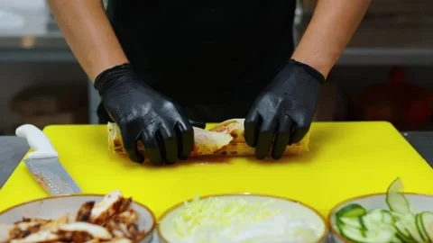 The cook cuts the shawarma into 2 pieces with a knife. Stock Footage 309818619