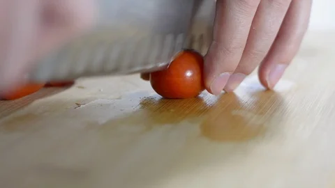 Cook cuts small cherry tomatoes on a wooden board Stock Footage 124190687