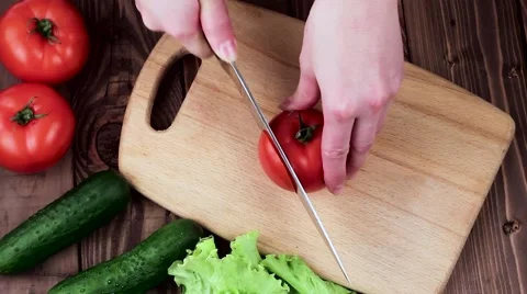 Cook Cuts Tomato on the Board. on the Table Are Cucumbers and Salad Leaves. Top Stock-Footage 61883498