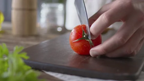 Cook cuts tomato with large kitchen knife on wooden kitchen cutting board. Close Video stock 144665849