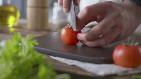 Cook cuts tomato with large kitchen knife on wooden kitchen cutting board. Close Video stock 145017294