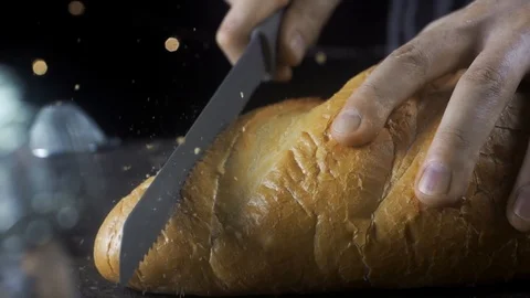 Cook cuts white flour bread with a knife in the kitchen , cooking in slow motion 動画素材 105367184