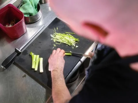 Cook cutting a celery using a sharp knife in a restaurant Stock Photos