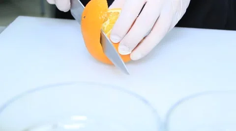 Cook is cutting an orange on white cutting board Stock Footage 48397712