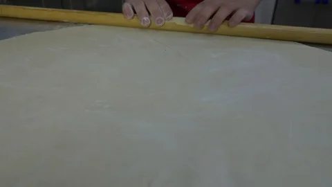 The cook on the cutting table rolls out the dough Stockbeeldmateriaal 88898260