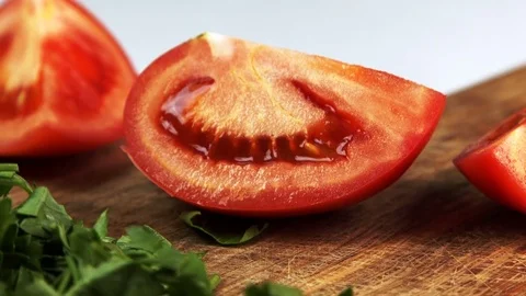 Cook is cutting tomato slice in half on table in home kitchen. Stock Footage 82151826