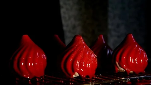 Cook decorates the red mousse cake with mirror glaze gold glitter. In the frame Stock Footage 76122247