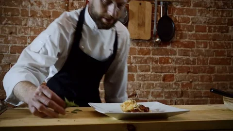 The cook decorating the finished dish of potatoes, cream, herbs and cheese. 4K Stock Footage 83153066