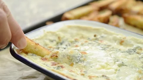 The cook dips crispy bread into the hot spinach dip. Stock Footage 207020971