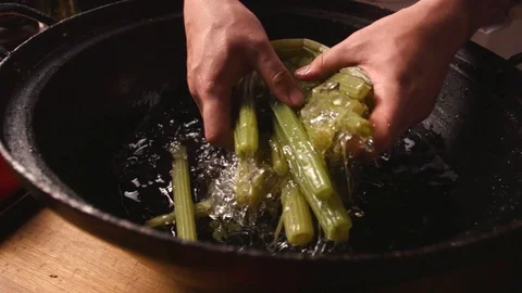 A cook dips an edible burdock in ice water to cool. Stock Footage 119189802