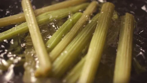 A cook dips an edible burdock in ice water to cool. Stock Footage 119189803
