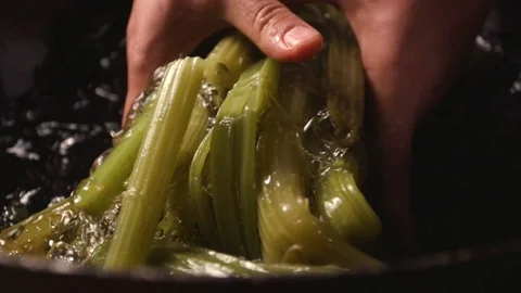 A cook dips an edible burdock in ice water to cool. Stock Footage 119189811