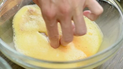 The cook dips the pork loin in the eggs mixture. Stock Footage 200810825