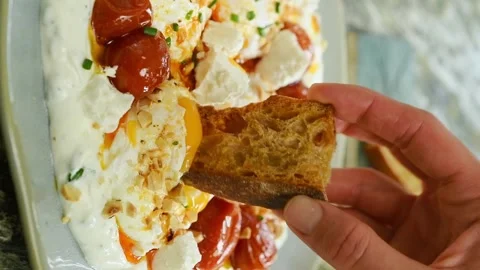 The cook dips a slice of bread into the poached eggs. Vertical video. Stock Footage 311046154