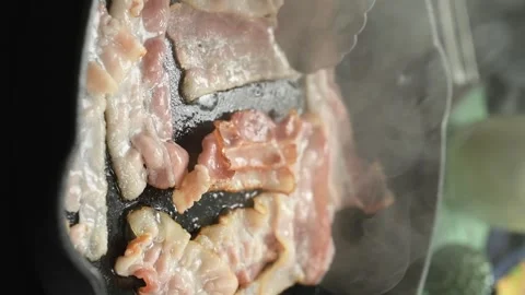 The cook flips bacon slices to the other side into the pan. Vertical video. Stock Footage 305154704