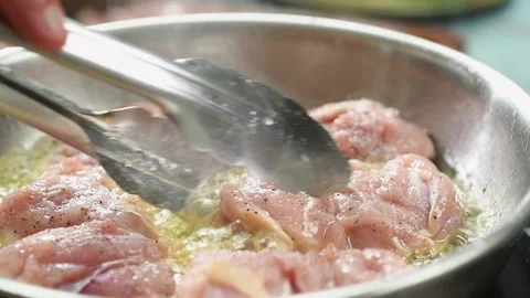 The cook flips the chicken meat in the frying pan. Stock Footage 210717871