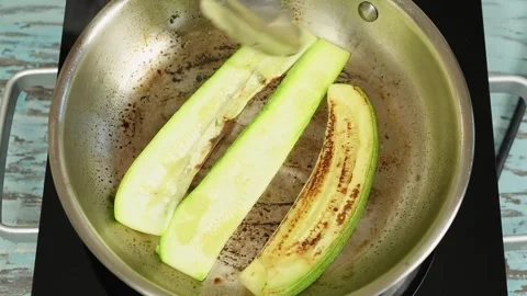 The cook flips courgettes to the other side into the pan. Stock Footage 247895760