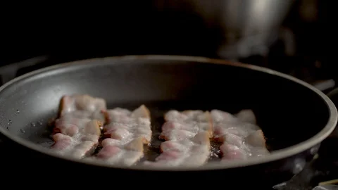The cook flips the fried bacon in a pan. Close up view Stock Footage 129574118