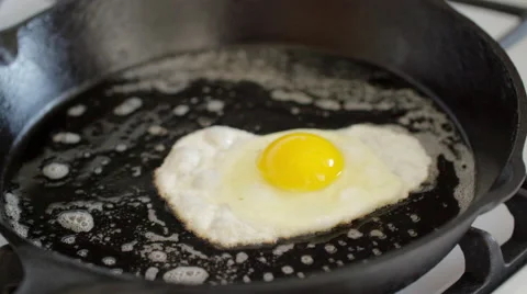 Cook flips fried egg over in a cast iron pan 4K Stock Footage 48572963