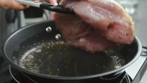 A cook flips juicy turkey breast in a pan. Stock Footage 171186653