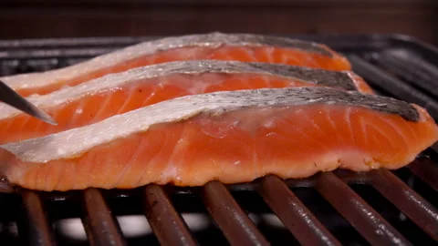 Cook flips a piece of delicious raw salmon steak with metal tongs Stock Footage 129118070