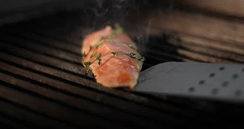 Cook flips a piece of fresh red fish sirloin on an electric grill using metal Stock Footage 120032730