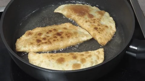 The cook fries meat chebureki in hot oil in a frying pan, close-up shot. Stock Footage 288175053