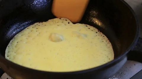 The cook fries pancakes on a cast-iron frying pan Stock Footage