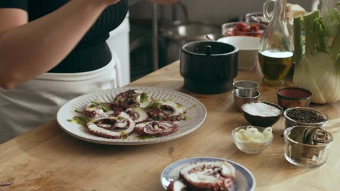 Cook garnishing octopus on a plate creating an octopus carpaccio dish in a large Video stock 199461079