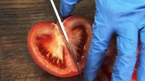Cook in gloves cuts half tomato in kitchen of restaurant. Stock Footage 82160659