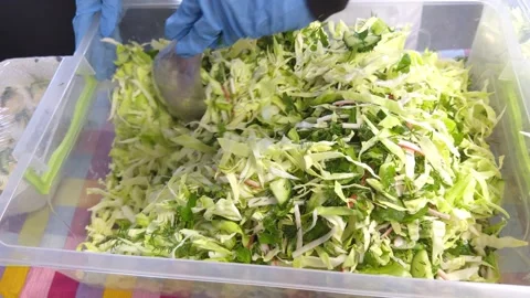 Cook in gloves mixing cabbage salad in a large plastic container in a canteen Vídeos de archivo 333622374