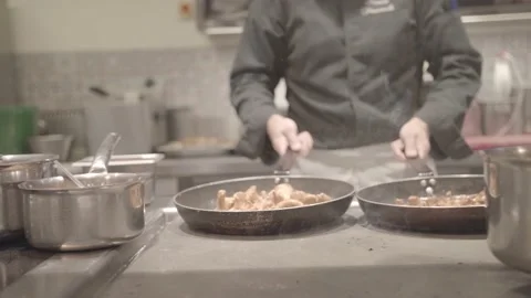 A cook grabs two frying pans filled with mushrooms and bounces them around Stock Footage 135399797