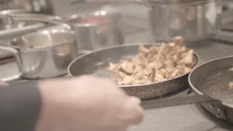 A cook grabs two frying pans filled with mushrooms, close-up Stock Footage 135399853