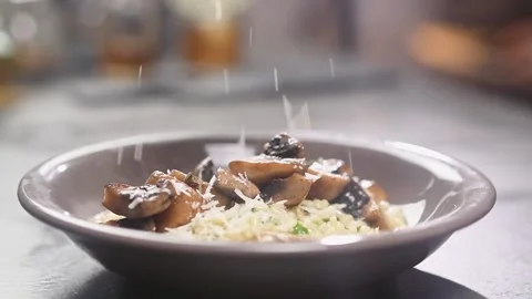 The cook grating parmesan cheese on risotto with mushrooms, served on a plate. Stock Footage 154370596