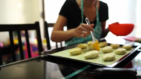 Cook greases the buns on a baking sheet with a brush with a beaten egg Stock Footage 280318919