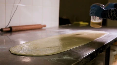 Cook greases a large sheet of dough with a brush and egg Vidéo 106467365
