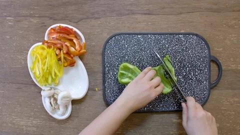 Cook hands cut green pepper on a black board on a table with a large cook knife Stock-Footage 122200384
