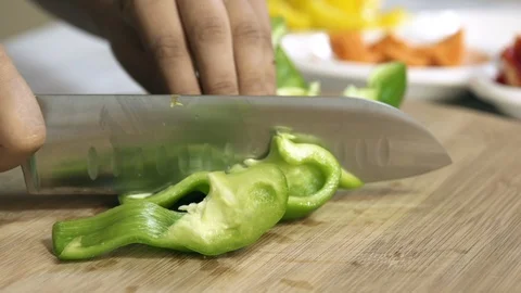 Cook hands cut green pepper on a wooden board on a table with a large cook knife Stock-Footage 122235110