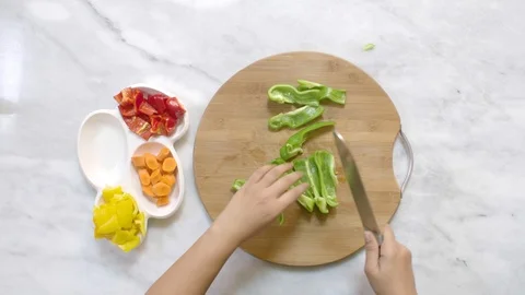 Cook hands cut green pepper on a wooden board on a table with a large cook knife Stock Footage 122235313