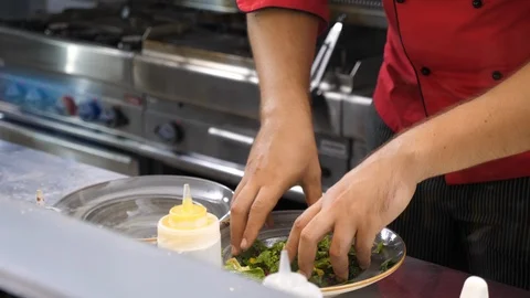 Cook hands in restaurant kitchen preparing a plate for clients Video stock 95884842