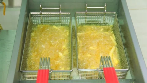 The cook hands shaking a basked full of french fries being prepared in hot bo Stock Footage 127715663
