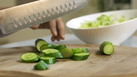 Cook hands slice cucumber on a black board on a table with a large cook knife Stock Footage 122235218