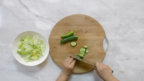 Cook hands slice cucumber on a black board on a table with a large cook knife Stock Footage 122235475