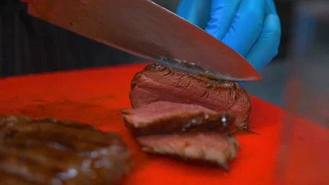 Cook of a high-level restaurant cuts steak into slices for a full-course dinner Stockbeeldmateriaal 218860077