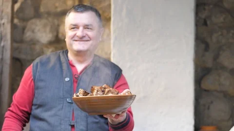 Cook holds in his hands an earthenware dish of fried pieces of beef liver Stock Footage 125696225