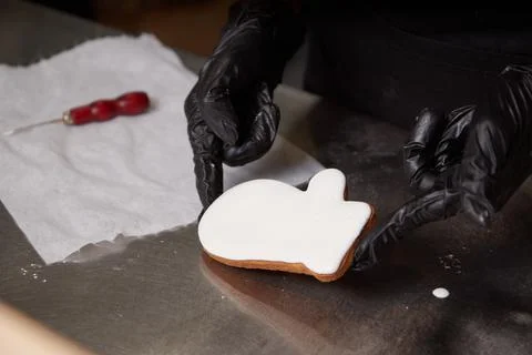 The cook holds a ready made cookie covered with white icing with his gloved Stock Photos