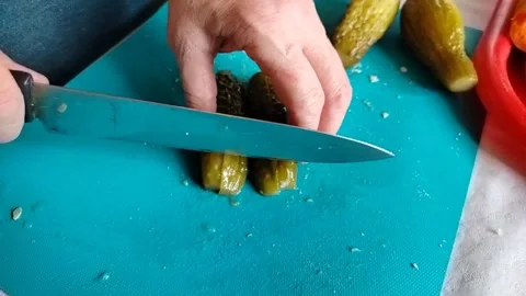 A cook in a home kitchen cuts pickles for a salad Stock Footage 306594852